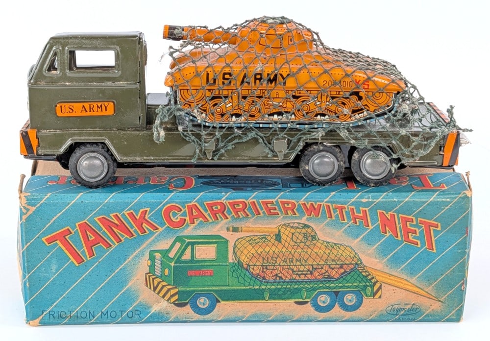 Japan Tin Friction Tank Carrier Truck with Net in Box: Toymaster Japan tin friction U.S. Army tank carrier truck with net in the original box. The truck has some paint crazing and dust from display. The box has some peeeling and minor wear from handling /