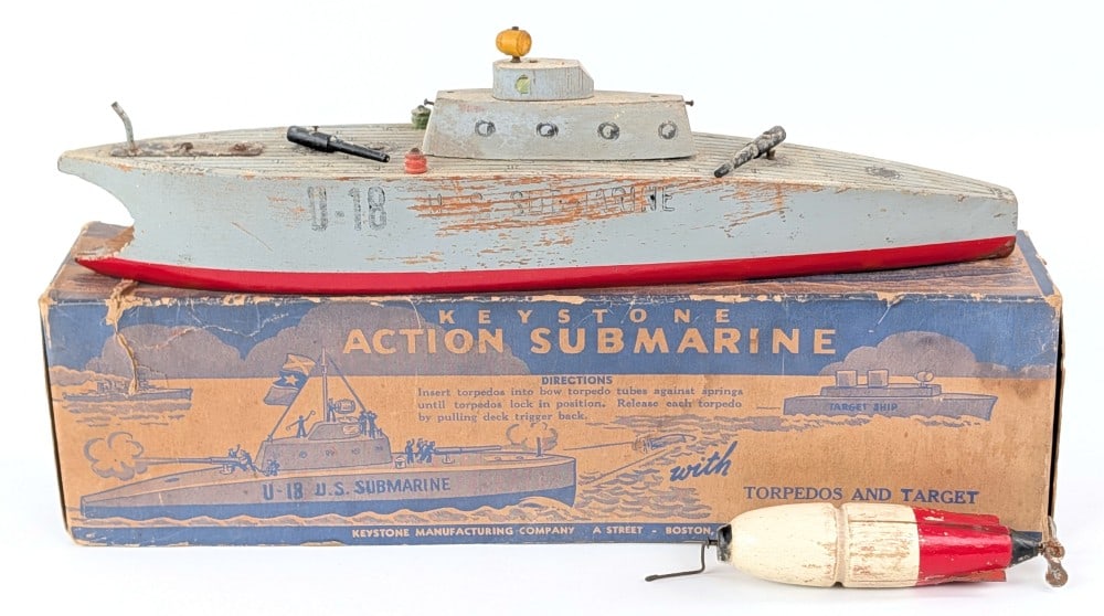 Keystone Submarine with Box: Keystone wood toy submarine. It comes with the torpedo but is missing the target ship. Shows wear from play and age. The box shows some soiling and wear / tear. Measures approximately 13" long.
