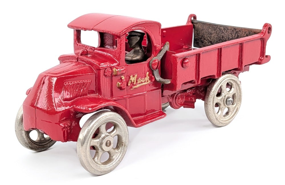 Arcade Cast Iron Mack Dump Truck: Arcade cast iron Mack dump truck. The truck has a very nice restoration. The truck is painted in red overall with embossed "Mack" in gold lettering on the doors and spring loaded dump bed. Has some du