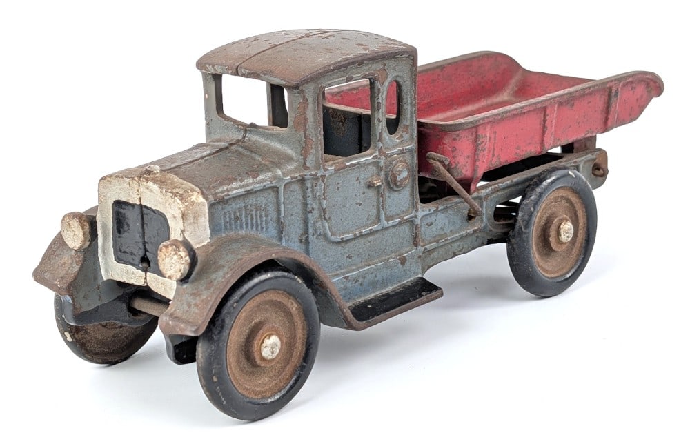Kilgore Cast Iron Dump Truck: Kilgore cast iron dump truck. The truck has some old paint enhancements notably to the radiator area. The truck shows paint loss and wear from age. Measures approximately 8-1/2" long.
