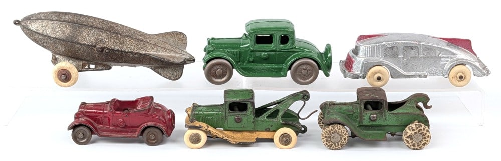 Cast Iron Tow Trucks, Zeppelin, and Cars: Cast iron tow trucks, zeppelin / blimp, and cars. Condition varies from original to restored. Largest measures 6" long.