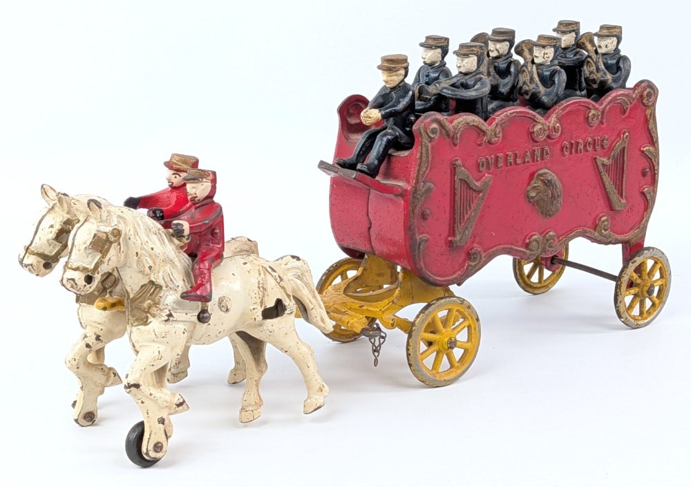 Kenton Cast Iron Overland Circus Band Wagon: Kenton cast iron Overland Circus band wagon. Has one replacement rider. Includes six musicians, one driver, and two horse riders. Showing paint loss and play wear. Measures approximately 15" long.