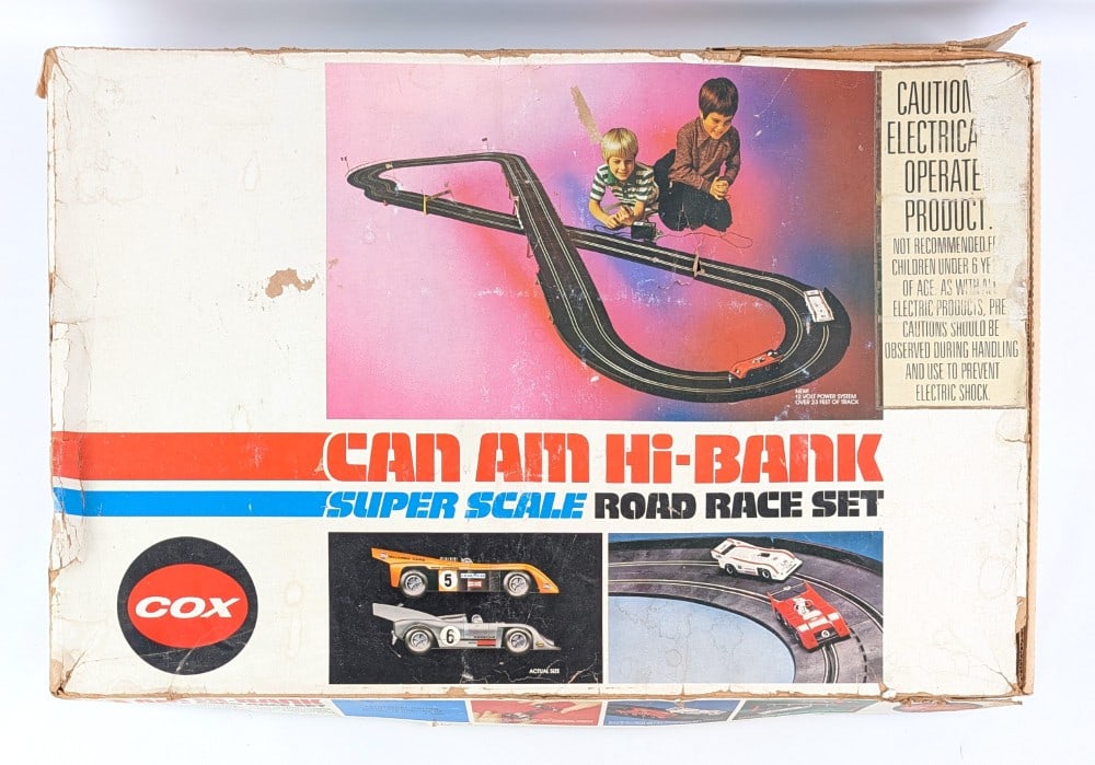 Cox Can Am Hi-Bank Super Scale Road Race Slot Car Set: Cox Can Am Hi-Bank Super Scale Road Race slot car set in the original box. The set comes with the two cars, controllers, track, and instructions sheet. The box has wear and tear from handling / age.