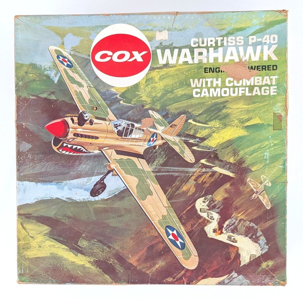 COX Curtiss Warhawk P-40 Engine Powered Plane with Box: COX Curtiss Warhawk P-40 gas engine powered airplane with combat camouflage in the original box. The plane is dusty / dirty from storage and use. The box has some tape repairs, punctures, and wear fro