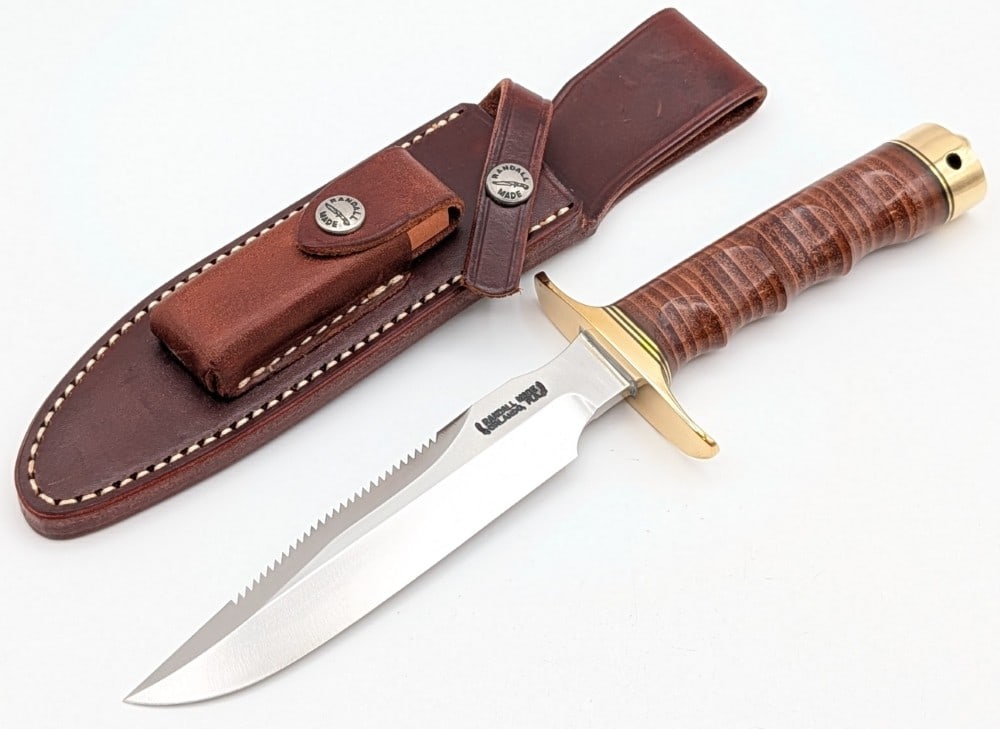 Randall Model 1 6in Sawtooth Finger Groove All Purpose Fighter w/ Sheath: Features a saw tooth grind spine, a brass double guard, a finger groove stacked leather handle, a brass butt cap with a lanyard hole, and a nut pommel. Knife is in like new condition. Blade length mea