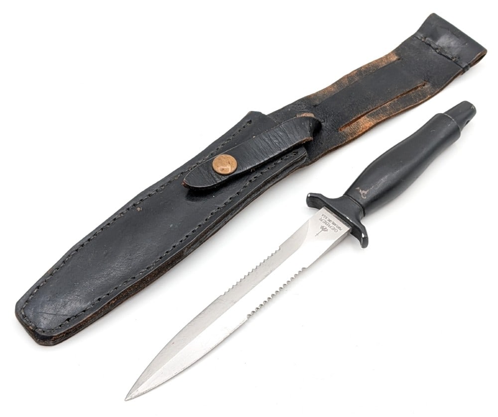 1984 Gerber Mark II Wasp Fighting Knife w/ Sheath: Features a serrated double edged blade, and an integral guard and handle coated in a fused armorhide coating. Knife is in used condition with some heavy scratches on the blade, and finish wear on the 