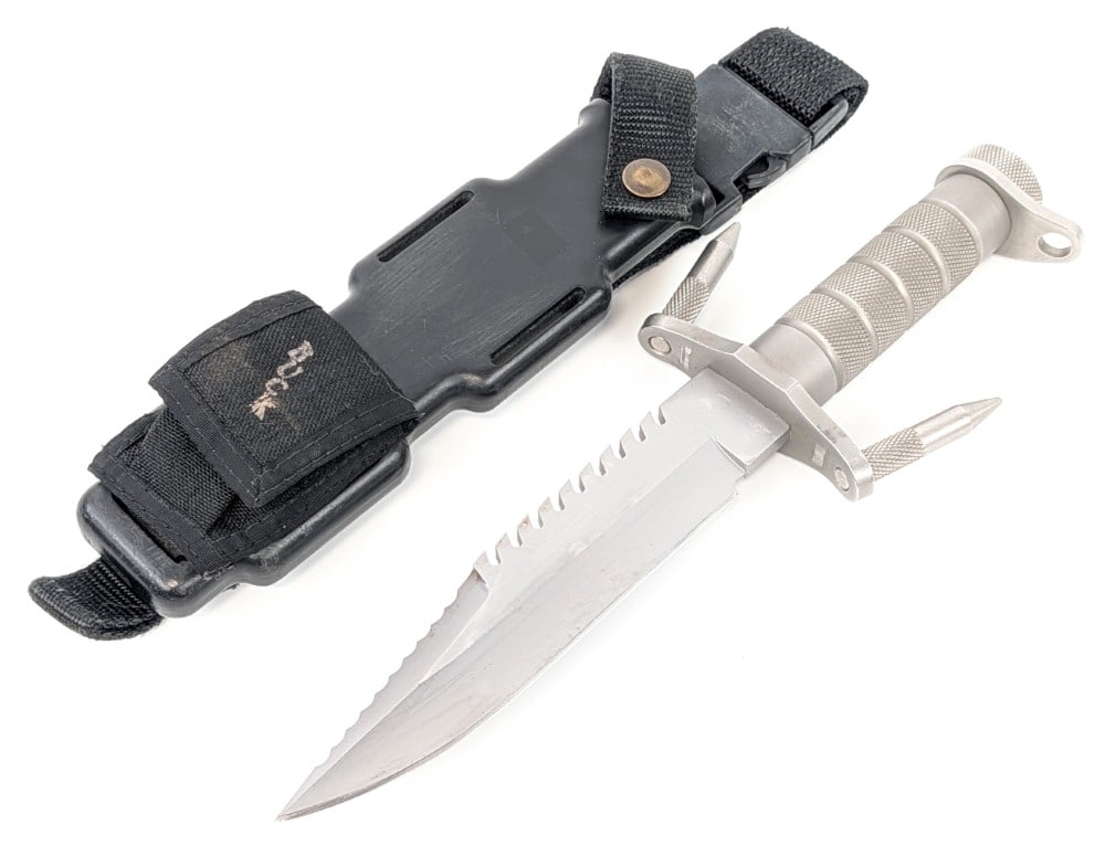 Buck Knives Buckmaster 184 Survival Hunting Knife w/ Sheath: Features a bead blasted blade with a sharpened serrated top edge, double upturned guard with removeable spikes, and a hollowed knurled tube handle. Knife is in good used condition with some scratches 