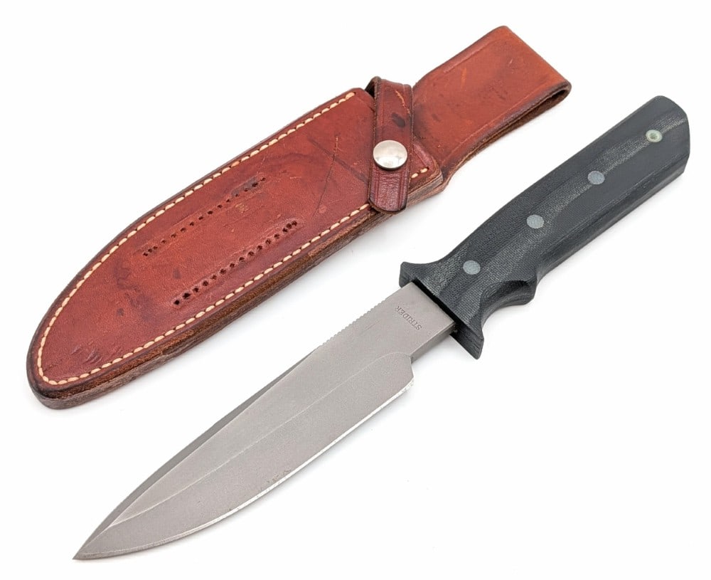 Mick Strider Knives MT Fixed Blade Knife w/ Signed Randall Sheath: Consigner received this knife in the Randall sheath, which fits very well, then met Strider at a knife show and had him sign the sheath. Features a bead blasted drop point blade with thumb notches, an