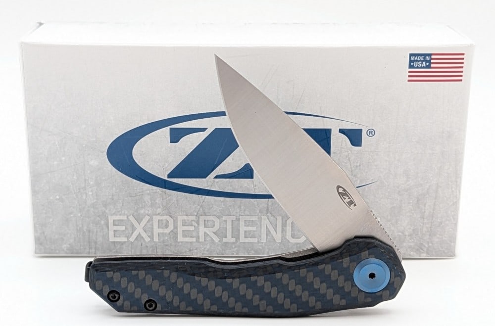 NIB Zero Tolerance ZT Model 0545 Flipper Folding Knife: Features a stonewash finish titanium handle and a black and blue carbon fiber handle scale. Knife is in new condition. Overall measures 4-1/4in when closed.