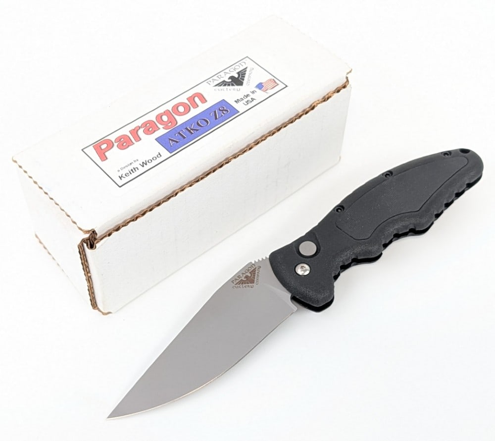 Paragon Cutlery ATKO Z8 Auto Switchblade Knife: Features a drop point blade with a gray finish, black plastic handle, and rubber grip inserts. Knife is in like new condition with minimal wear from handling. Overall measures 4-1/2in when closed.