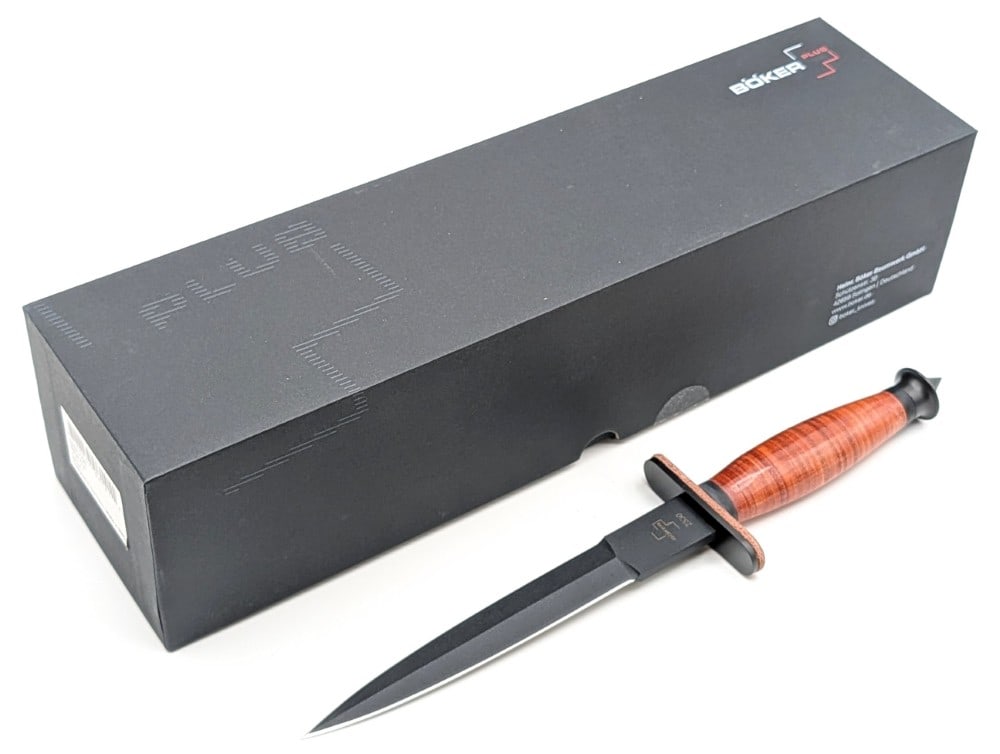 Boker Plus V-42 Dagger w/ Box & Sheath: Features a black finish double edged blade, a black finish double guard, a stacked leather handle, and a crusher pommel. Knife is in new condition. Blade length measures 6-7/8in and overall 12-1/8in.