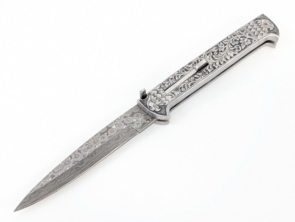 Custom 11in Damascus Steel Engraved Switchblade Knife: Features a damascus blade, and a full steel handle with engraved beak bolsters. Knife is in like new condition. Overall measures 6in when closed.