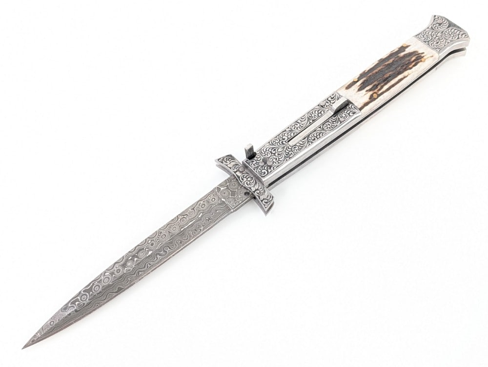Custom 13in Engraved Damascus Stag Swing Guard Switchblade Knife: Features a damascus blade, an engraved swing guard, engraved steel handle and bolster, and stag inserts. Knife is in like new condition. Overall measures 7in when closed.