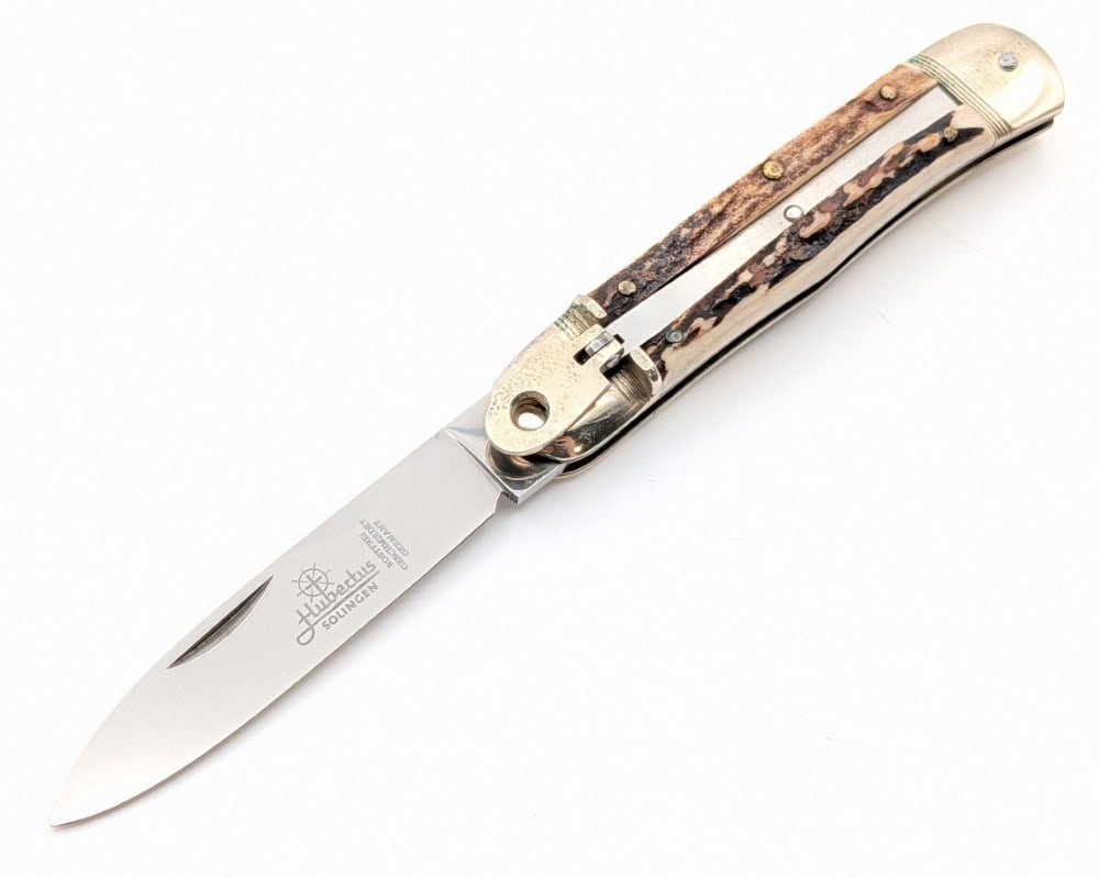 Hubertus Solingen Stag Leverlock Switchblade Knife: Knife is in fair condition with minimal scuffs on the blade, and tarnishing and dings on the bolsters from handling. Overall measures 4-1/2in when closed.