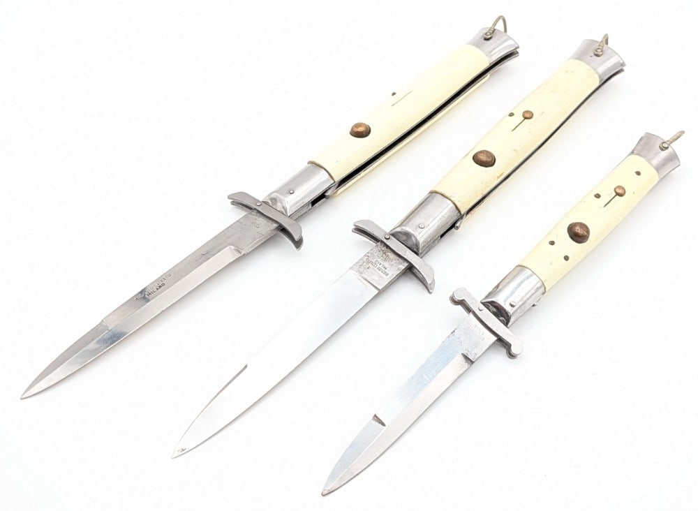 (3) Rizzuto Estileto Synth White Swing Guard Switchblade Knives: Knives are in fair aged condition with light scratches on the blade, scuffs on the bolsters, and scratches and wear on the handle scales. Blade springs work and lock tight when open. Overall measures