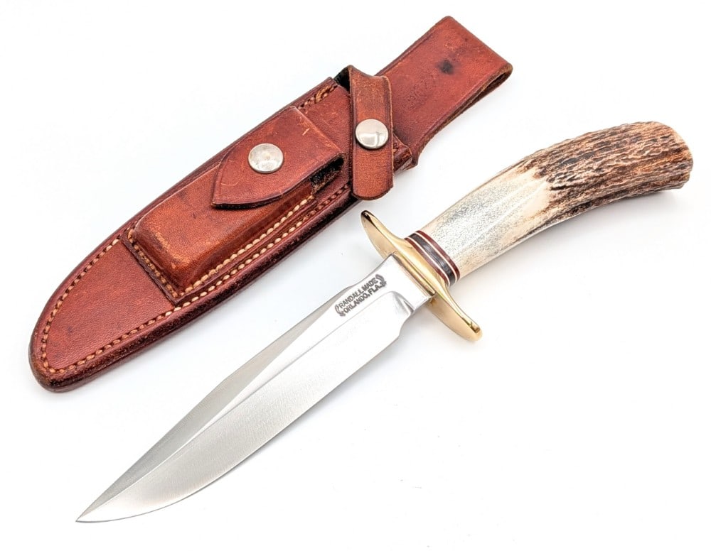 1970's Randall Model 1 6in Stag All Purpose Fighter w/ Sheath: Features a brass double downturned guard, and a stag handle. The sheath is missing the stone. Knife is in very nice condition with traces of scratches on the polished blade. Blade length measures 5-7/