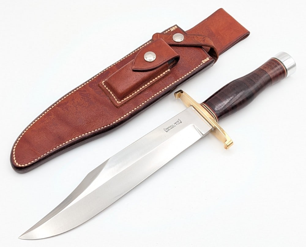 1970's Randall Model 12 Confederate Bowie Knife w/ Sheath: Features a large named clip point blade "Ron Pick", a brass double lugged guard, a stacked leather handle, a duralumin butt cap, and a nut pommel. Knife is in very nice condition with light scuffs on 