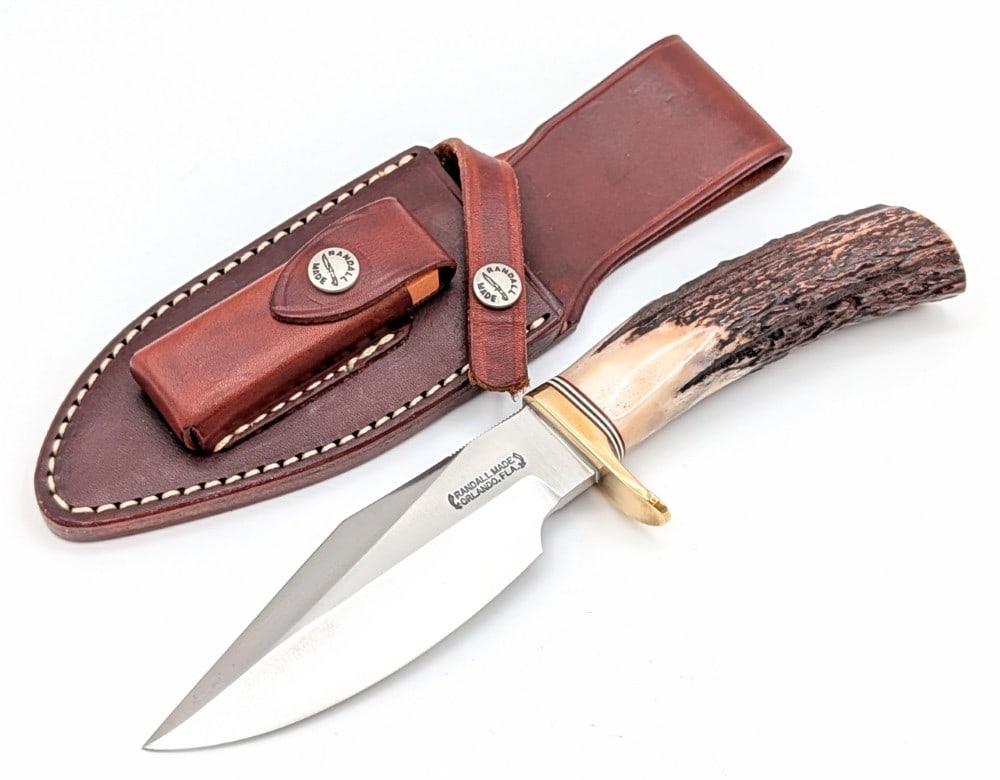 Randall Model 19 Stag Bushmaster w/ Sheath: Features thumb notches on the blade, a brass single downturned guard, and a stag handle. Knife is in very nice condition with some traces of pits and scuffs on the blade, and light scuffs and tarnishi