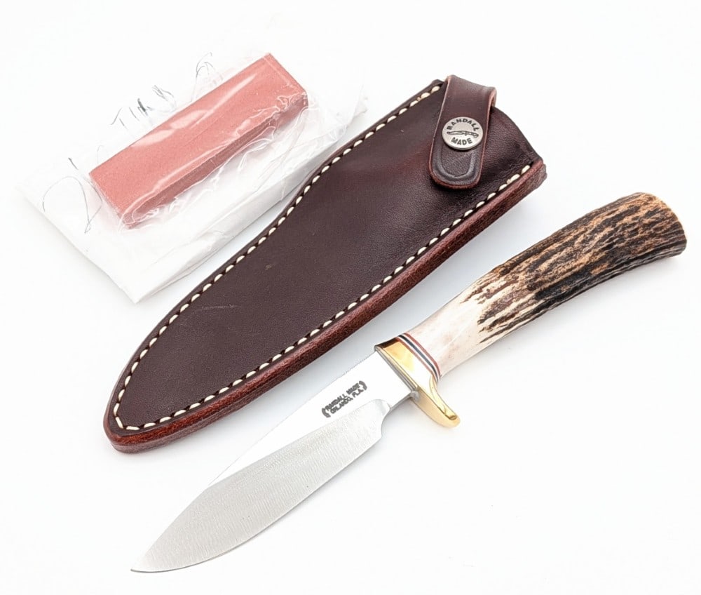 Randall Model 26 4in Stag Pathfinder w/ Sheath & Stone: Features thumb notches on the blade, a brass single downturned guard, and a stag handle. Knife is in new condition. Blade length measures 4in and overall 8-3/8in.