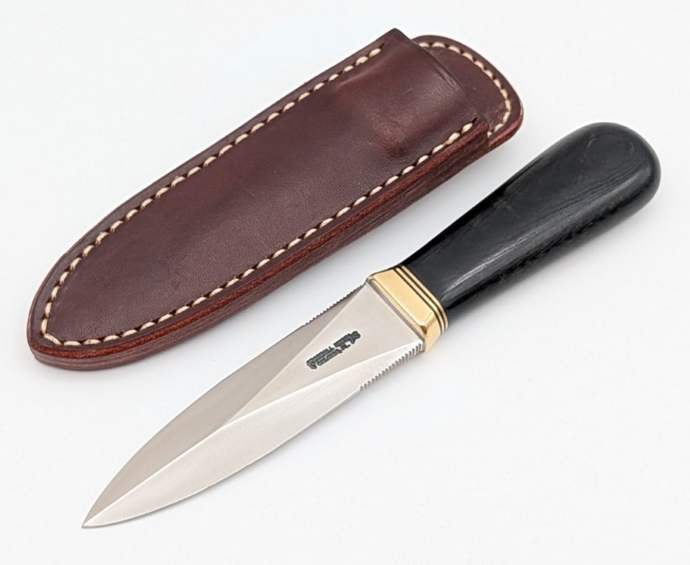 Randall Model 24 Black Micarta Guardian w/ Sheath: Features a stainless steel blade with thumb notches on either side, a reduced brass guard, and a black micarta handle. Knife is in like new condition. Blade length measures 4in and overall 7-3/4in.