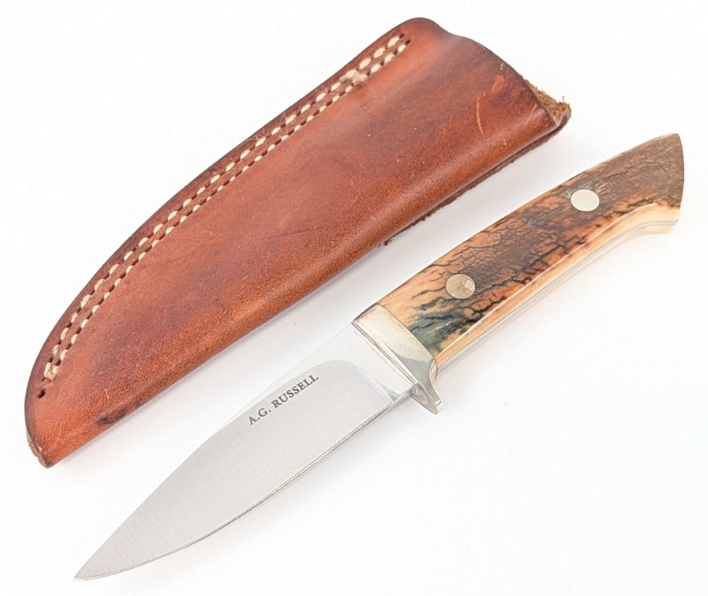 A.G. Russell Fossilized Mammoth Bone Drop Point Hunter w/ Sheath: Features a satin finish drop point blade, a polished steel guard, and mammoth bone handle scales with large pins. Knife is in very nice condition with light scuffs and tarnishing from handling. Blade 