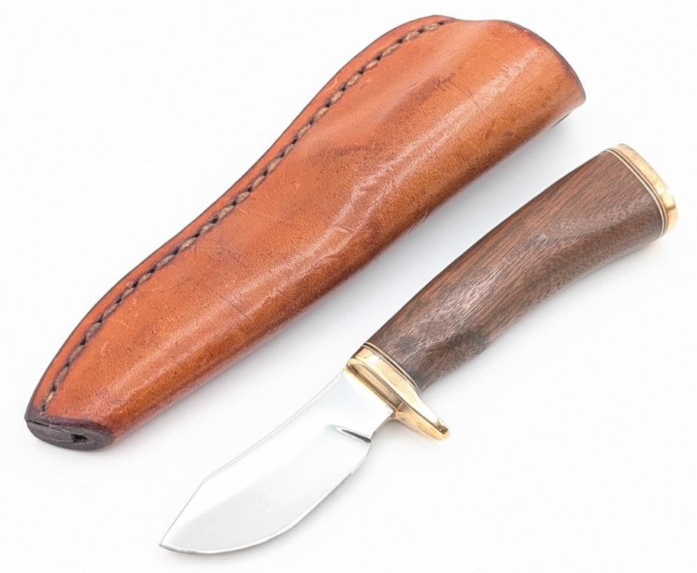 P.A.K. Martin J. Patterson Smooth Wood Clip Point Hunter w/ Sheath: Features a mirror finish clip point blade, a brass single guard, a smooth wood handle, and a brass butt cap. Knife is in good condition with some light scuffs on the blade, and light scuffs and tarnis