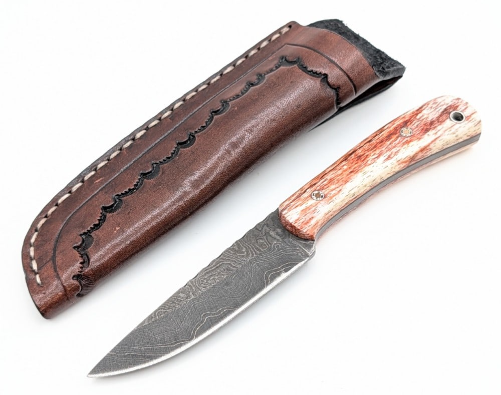 Custom Rocky Thomas Dyed Bone Damascus Fixed Blade Hunter w/ Sheath: Features a damascus full tang blade with file work along the spine, and pretty bone handle scales with mosaic pins. Knife is in like new condition. Blade length measures 3-3/4in and overall 7-5/8in.