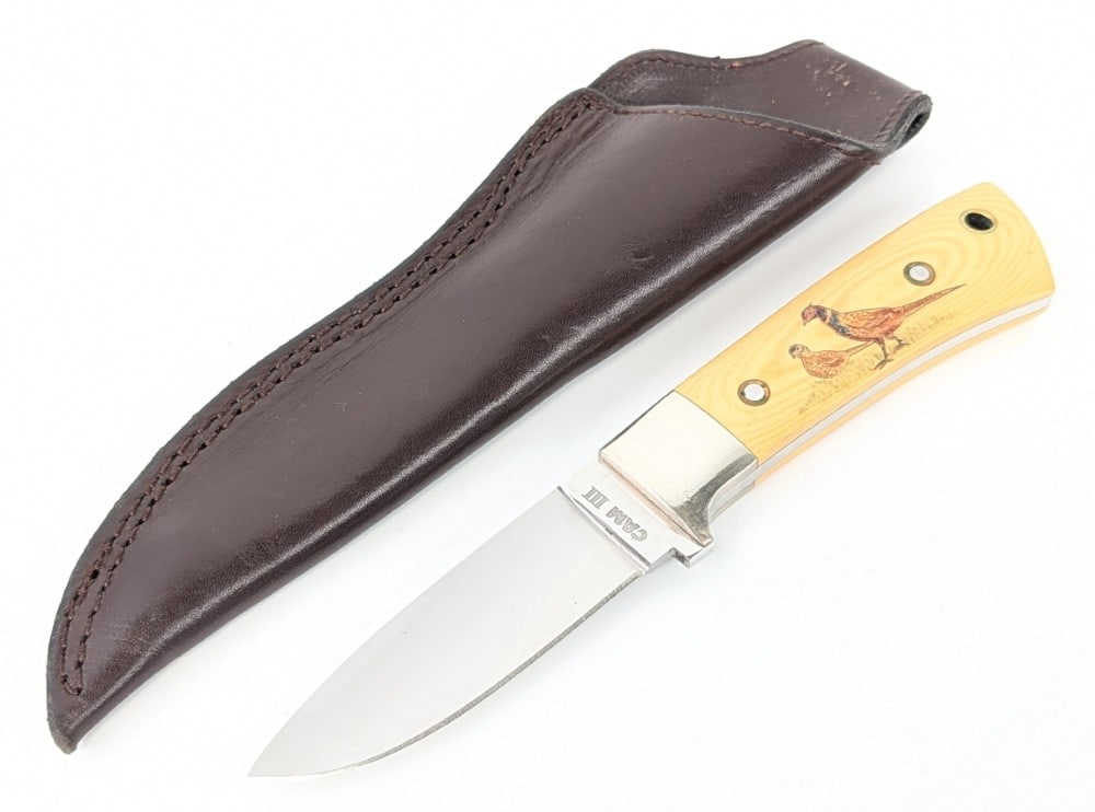 CAMIII Scrimshaw Yellow Micarta Drop Point Hunter w/ Sheath: Features a mirror polished drop point blade, nickel silver bolsters, and scrimshaw yellow paper micarta handle scales with a lanyard hole. Knife is in very nice condition with light scuffs and tarnish
