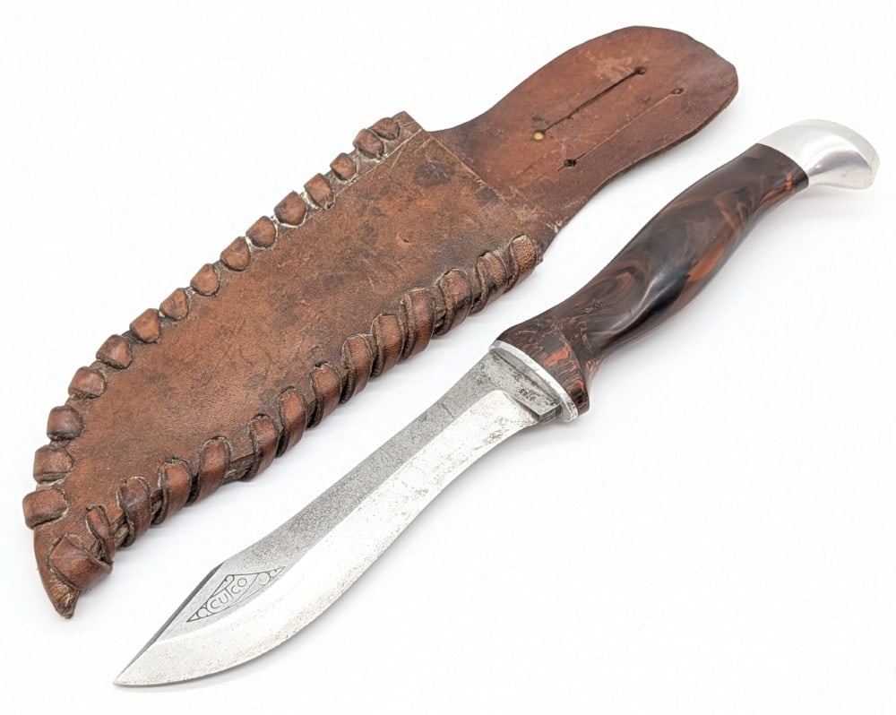 Cutco Model 1765 Explorer Hunting Knife w/ Sheath: Knife is in fair used condition with scratches and tarnishing on the blade, scuffs and wear on the handle, and dings on the aluminum pommel. Blade length measures 5-1/4in and overall 10-1/4in.