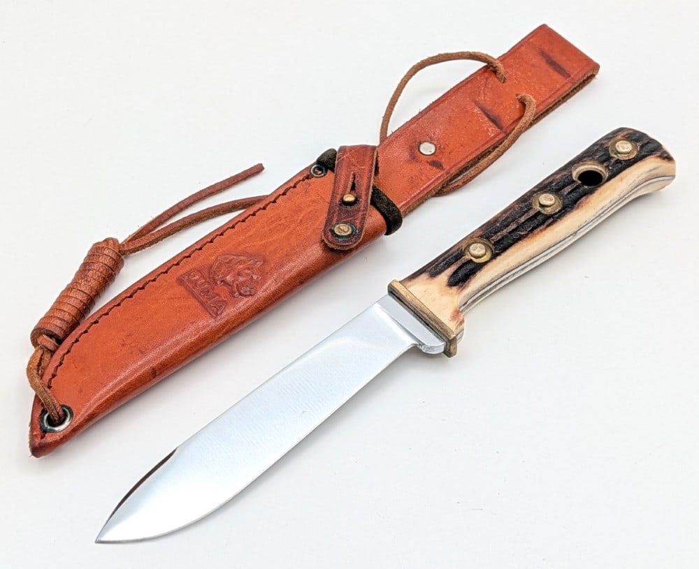 1971 Puma Stag Hunters Friend 6398 w/ Sheath: Features a semi mirror drop point blade with a fuller and thumb notches, a reduced brass guard, full tang handle, and stag handle scales with large brass pins and a lanyard hole. Knife is in nice used