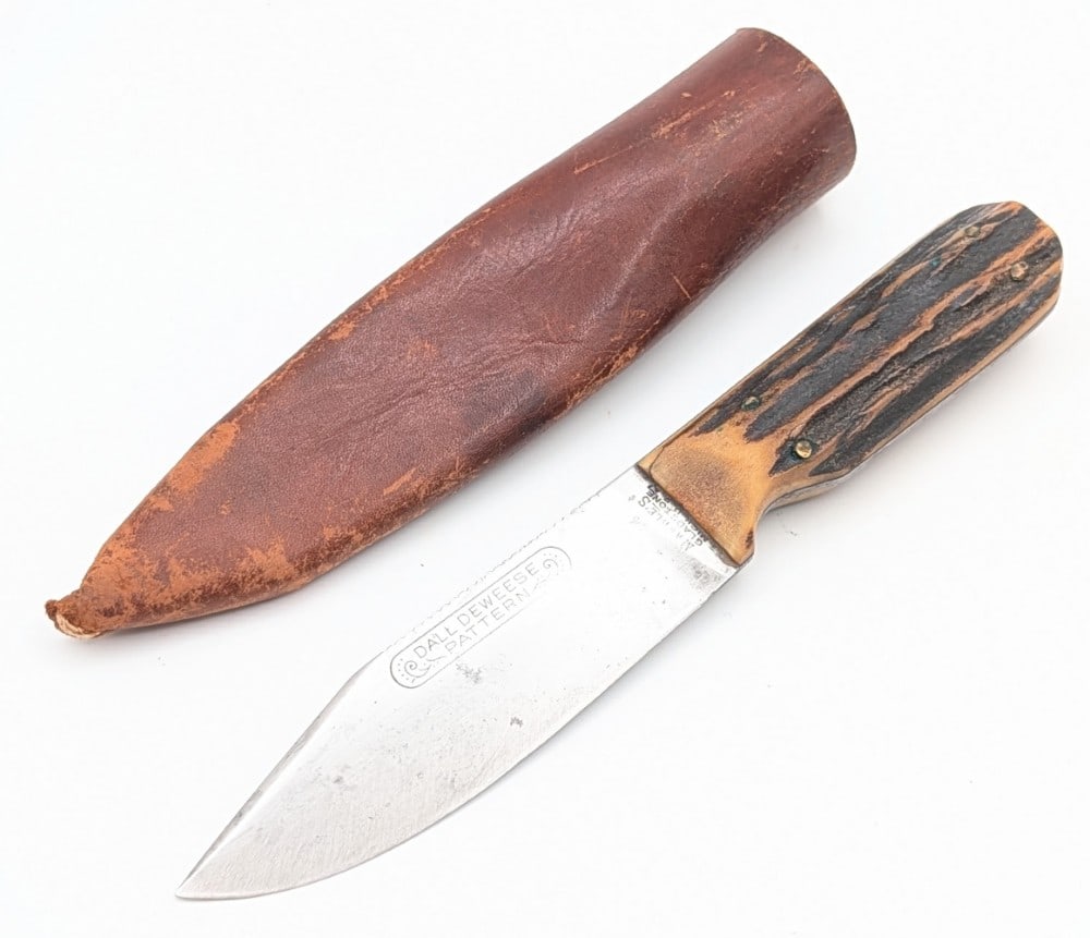 1912-23 Marble's Stag Dall Deweese Knife w/ Tube Sheath: Features a clip point blade with a course file spine and a left serif tang stamp, and stag handle scales. Knife is in good aged condition with scratches on the blade, some tarnishing, and a small crac