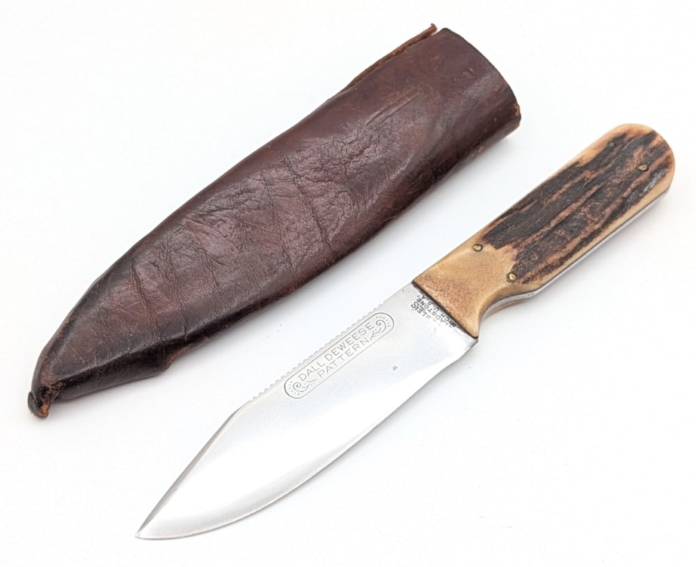 1912-23 Marble's Stag Dall Deweese Knife w/ Tube Sheath: Features a clip point blade with a course file spine and a roller coaster tang stamp, and thin stag handle scales. Knife may be from 1912-13 due to the thin stag handle scales. Knife is in good cleane