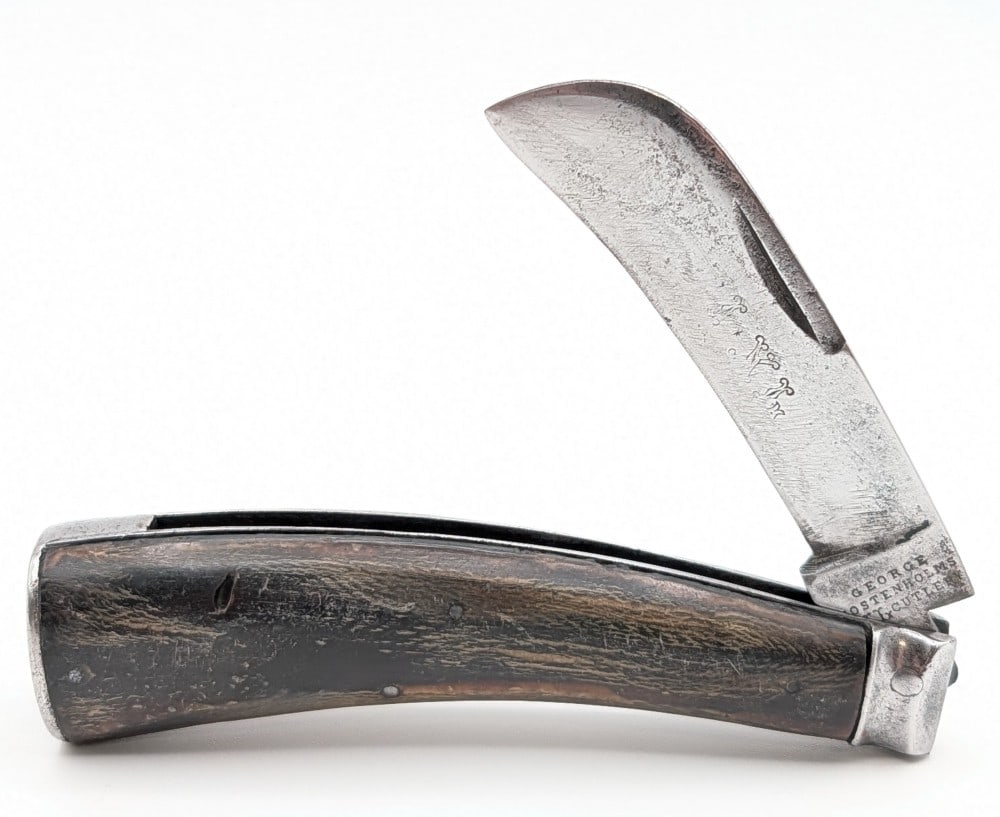 George Wostenholm IXL Smooth Buffalo Horn Hawkbill Folding Knife: Knife is in aged cleaned condition with heavy scratches and material loss on the polished blade, tarnishing and pitting on the bolsters and butt cap, and good aged handle scales. Overall measures 4-3/
