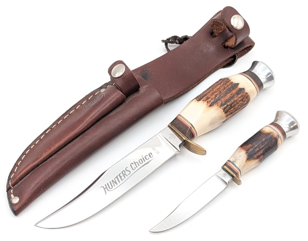 Kissing Crane Stag Hunters Choice Piggy Back Knife Set w/ Sheath: Knives feature mirror polished clip point blades, brass guards, stag handle scales with leather spacers, and aluminum pommels. Knives are in like new condition. Large blade length measures 5in and ove