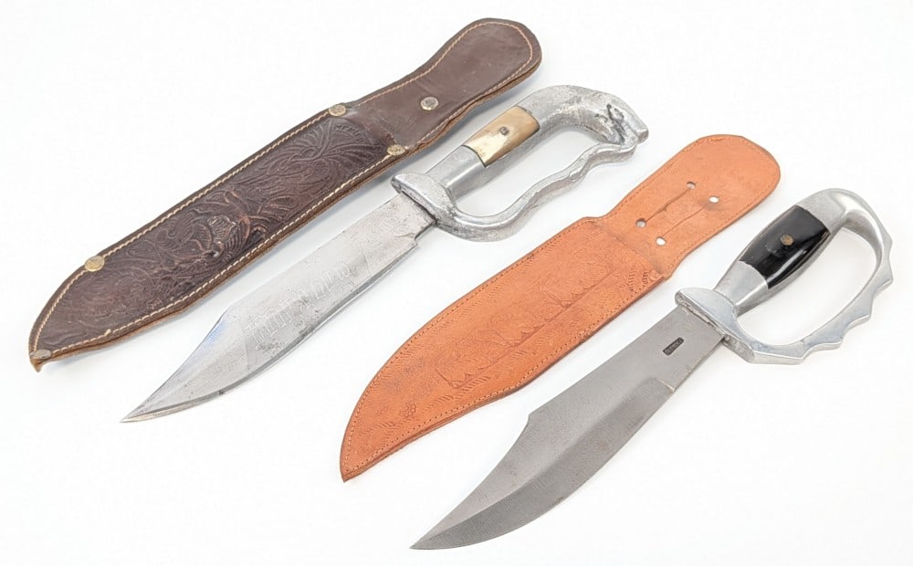 (2) Mexican Knuckle Guard Fighting Bowie Knives w/ Sheaths: Knives are in fair condition with scuffs and scratches on the blades, and scratches and roughness in the cast metal handles. Largest blade length measures 7in and overall 12in.