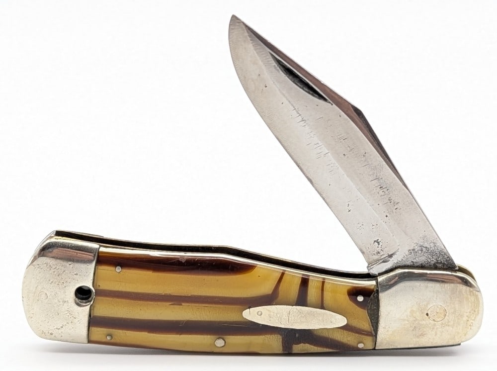 Western States Celluloid Gunstock Folding Knife: Knife is in well used condition with heavy scratches and material loss on the blade, scratches and dings on the bolsters, and scratches on the handle scales. Overall measures 4-1/2in when closed.