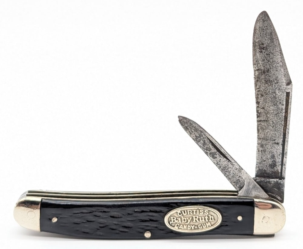 Remington Baby Ruth Curtiss Candy-Gum Rough Black Long Pull Jack Knife: Knife is in fair cleaned condition with heavy scratches and material loss on the blades, scuffs and dings on the polished bolsters, and nice handle scales. Overall measures 3-5/8in when closed.
