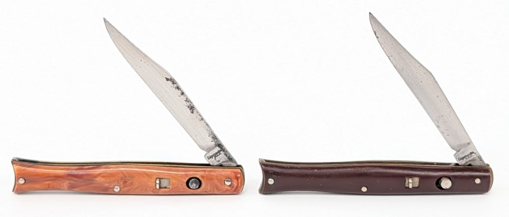 (2) Edgemaster Synthetic Fishtail Switchblade Knives: Knives are in fair aged condition with scratches and pits on the blades, and general wear on the handle scales from use and age. Both springs work fine, but the brown knife does not lock open. Overall