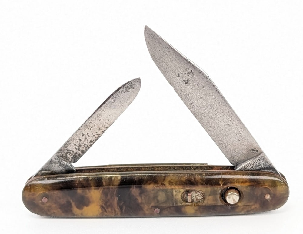 Schrade Cut Co. Tortoise Shell Celluloid Double Switchblade Knife: Knife is in fair aged condition with scratches and pits on the blade, and bad cracks on the back handle scale. Both springs work and the blades lock tight when open. Overall measures 3-3/4in when clos
