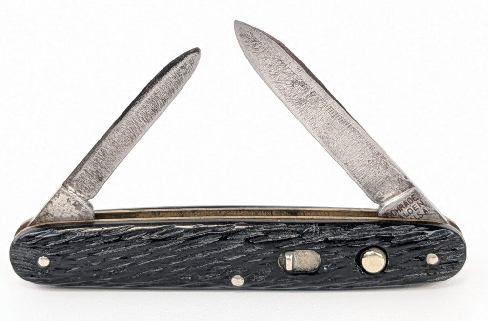 Schrade Walden Rough Black Double Switchblade Knife: Knife is in used condition with heavy scratches on the blade, and general scuffs on the handle scales. Both blade springs are strong and lock tight when open. Overall measures 3-3/8in when closed.