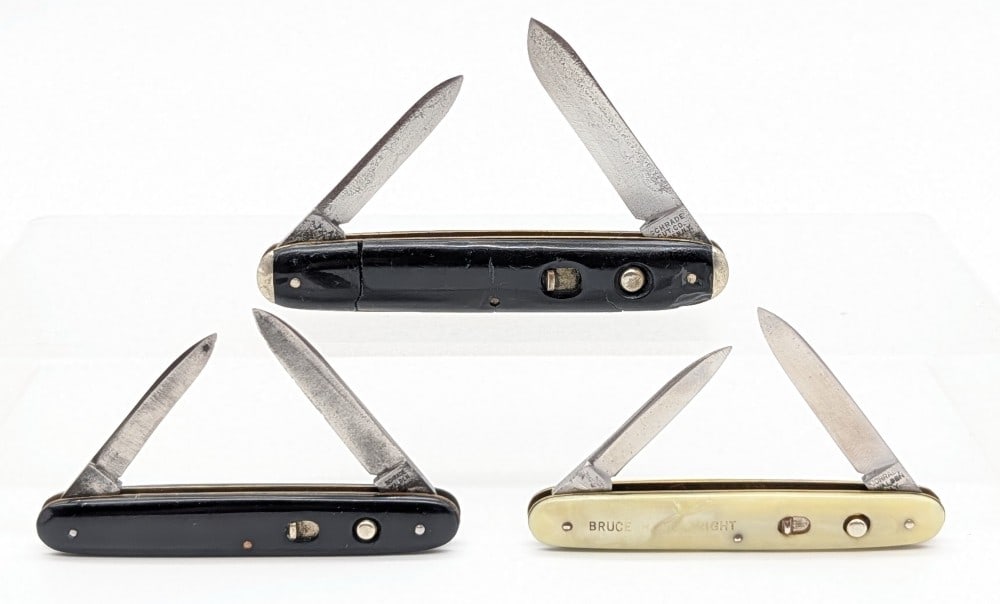 Schrade Walden Cut Co. Synth Black & White Double Switchblade Knives: Knives are in aged condition with scratches and pits on the blades, and cracks and scratches on the larger knife. Largest overall measures 3-3/8in when closed.