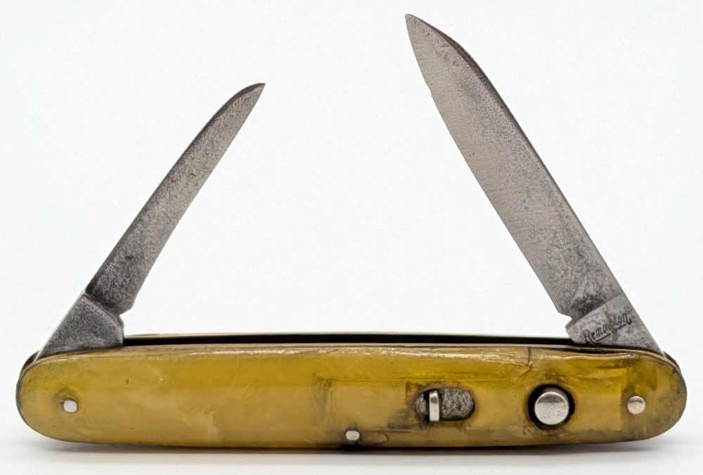 Remington Yellow Celluloid Double Switchblade Knife: Knife is in fair aged condition with material loss and tarnishing on the blades, and cracks and wear on the handle scales from age. Both blade springs are strong, and both blades have a fair bit of pl