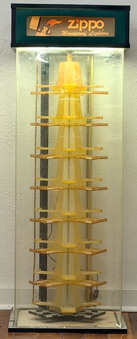 Zippo Lighter Store Display Case: Zippo Lighter Store Display Case. This Zippo display case features a tall clear plastic rotating carousel with the classic Zippo logo. The case is in good used condition, showing wear likely from age 