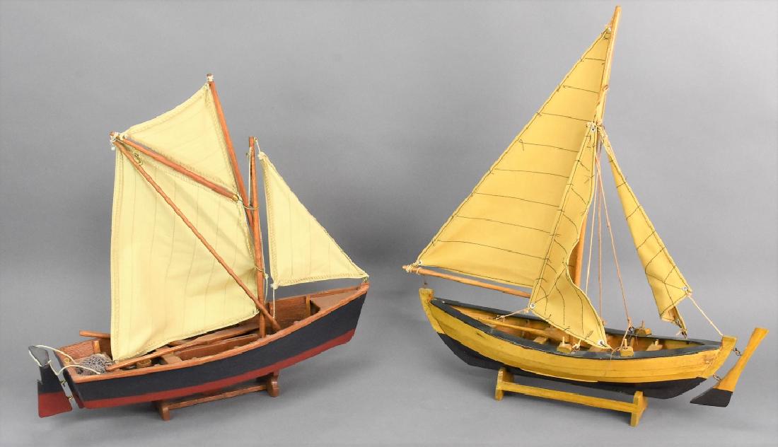Model Sailboat Grouping: Grouping includes (2) wooden Model Sailboats with display stands. The one boat has some loss to its bow, but can be repaired. The largest boat measures approx. 17.5"l by 19.5"h by 5"w and the other me