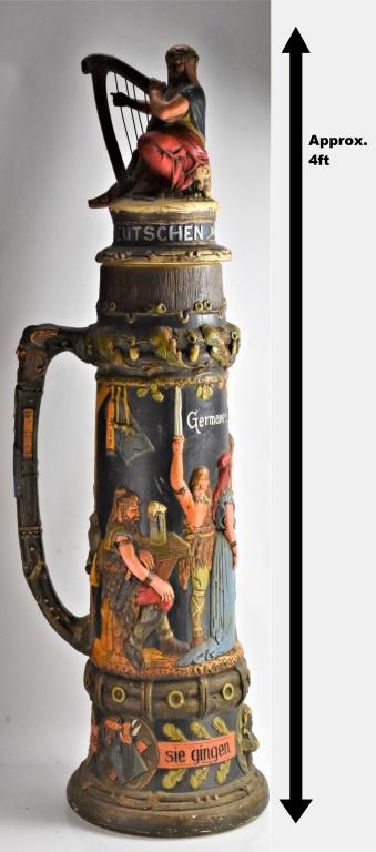 Kilian Beuler Wedding Stein: A large stein, believed to be Girmscheid and marked with the artist's initials "KB" (Kilian Beuler) depicting scenes from a wedding and measuring approx. 48"h. The foot of the figure on the lid has an