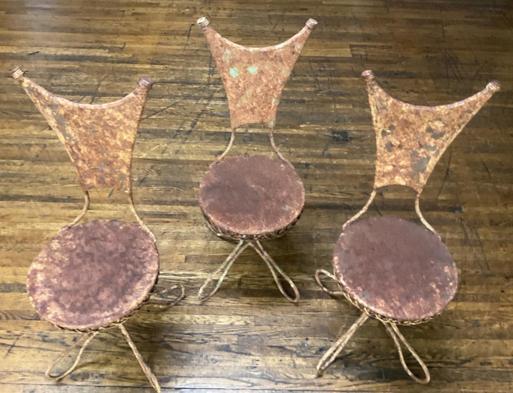 Mid Century Modern Wrought Iron Chairs: Grouping includes three rusted metal chairs. Each chair stands Approximately 38 inches tall. Seats are approximately 14 inches in diameter.