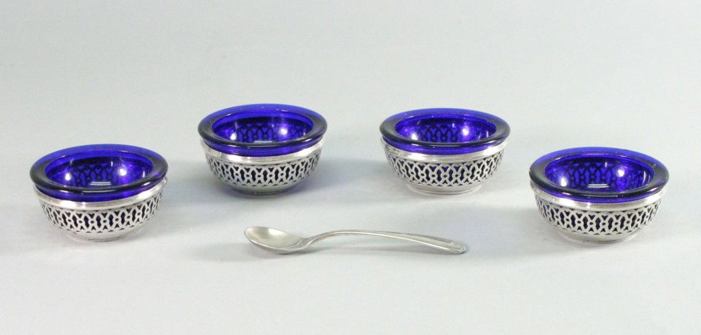 Sterling Silver Salts & Spoon With Cobalt Blue: A nice set of four Sterling Silver salts with Cobalt Blue liners and a Sterling spoon. Provenance: From the estate of Yvete Poher. Given to Mrs. Poher as a gift from listed artist John Koch.