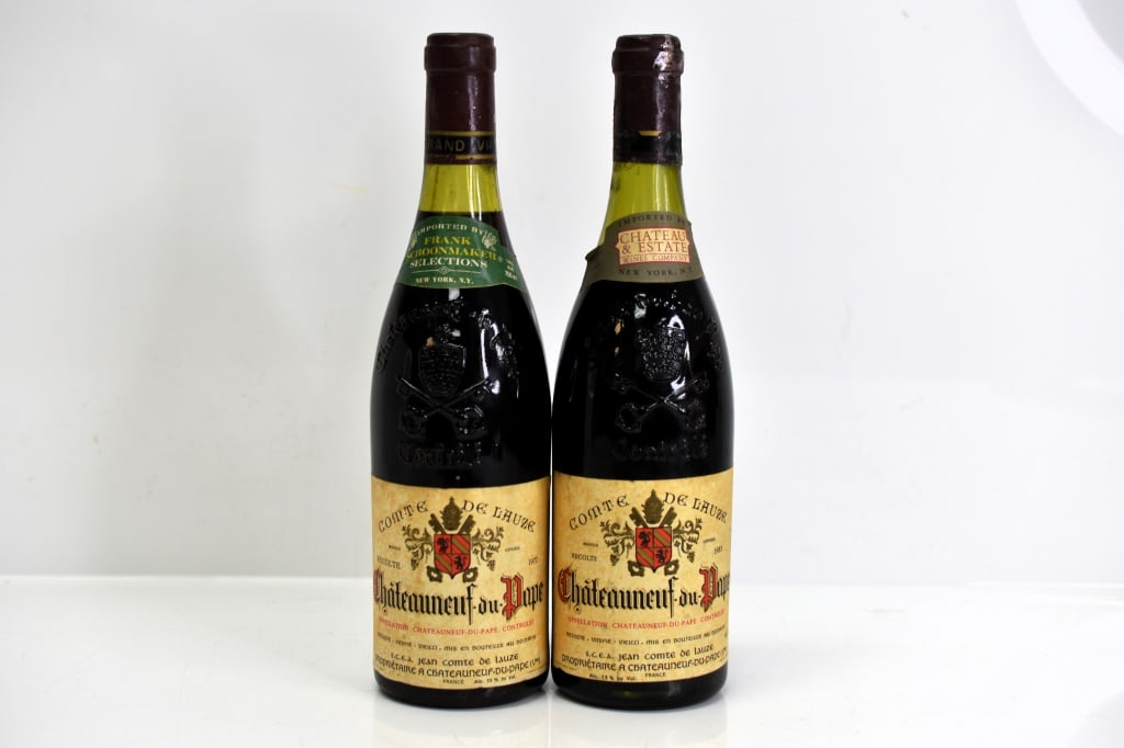 Comte de Lauze Chateauneuf-du-Pape Wine: Grouping includes (2) bottles of Comte de Lauze Chateauneuf-du-Pape red wine dated 1977 and 1983. One bottle appears to have a fill level at mid shoulder. This fine wine is part of an estate. It was s