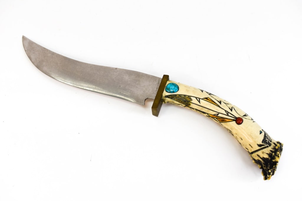 Vintage Ted Miller Custom Antler Knife: Hand carved antler with Native American Style depictions, inset turquoise, and coral stones. Signed at base of blade. Measures approx. 15.5"l Provenance: From a local estate, consignor states their mo