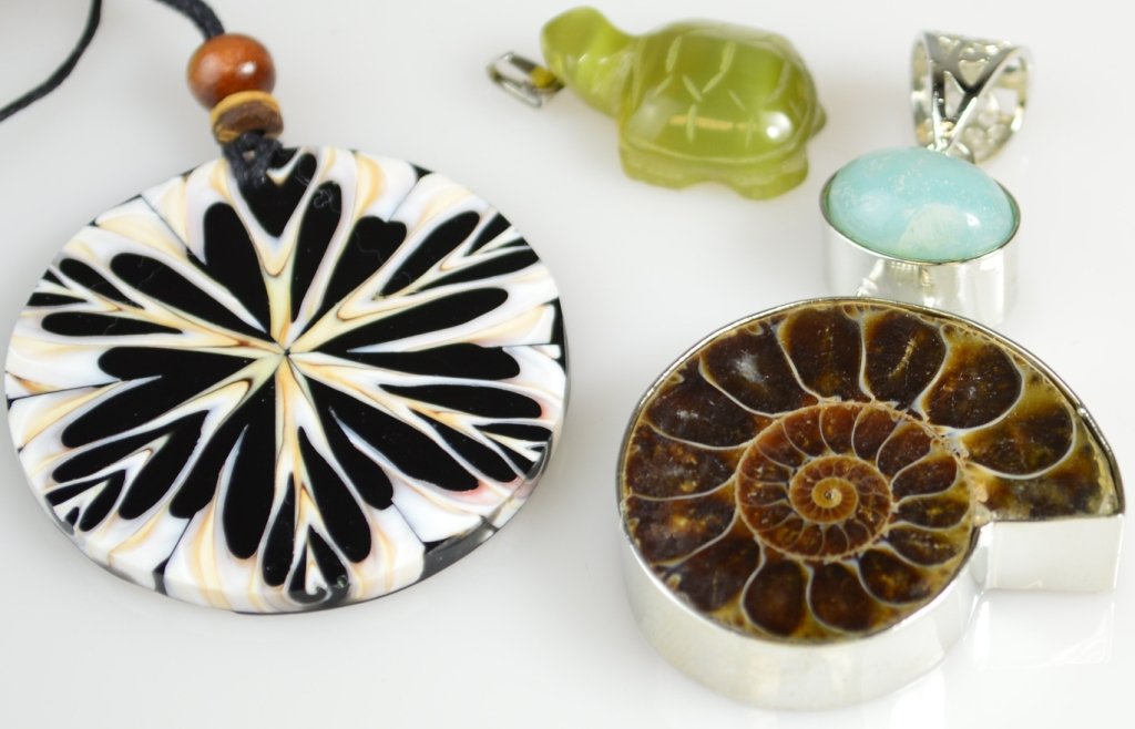 2 pendants and necklace grouping: Two pendants and necklace including green fiber optic glass carved turtle pendant; fossilized shell pendant; and shell disc on black cord necklace